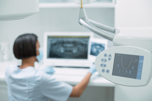 Investing in advanced technologies is one of the five dental industry trends you can implement this year. dental professional works with x-ray machines. 